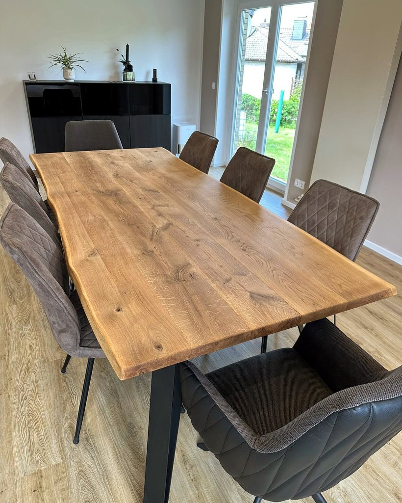 Massiv Holztisch mit echter Baumkante kombiniert mit schwarzem Untergestell und acht Polsterstühlen