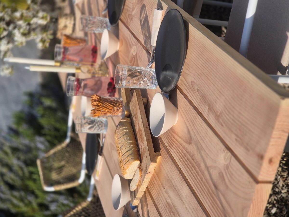 Gedeckter Gartentisch aus Douglasien Holz mit Geschirr und Snacks