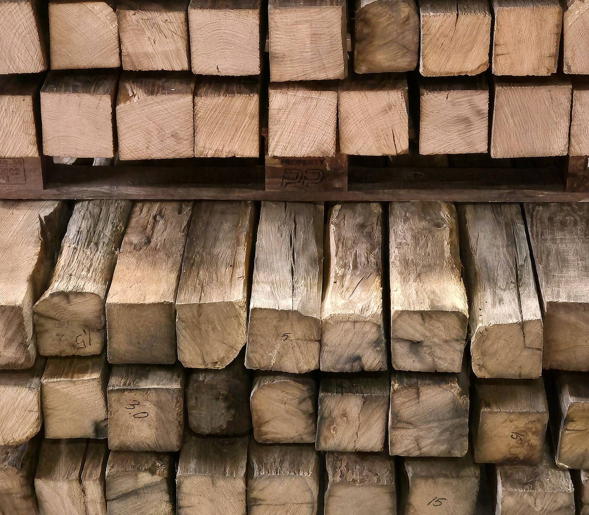 Gestapelte Altholzbalken aus Eiche – natürliche Farbunterschiede und authentische Struktur